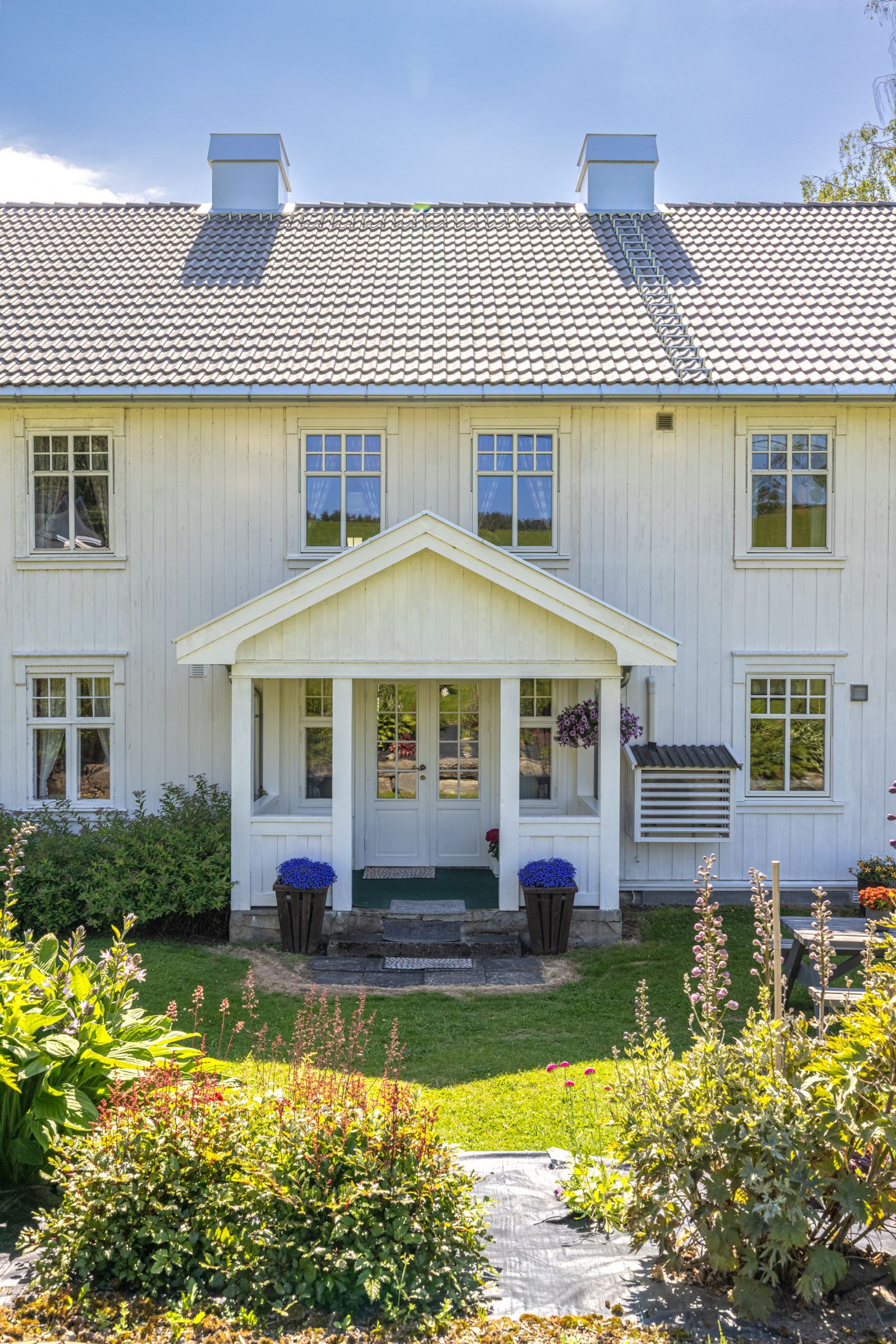 Ved inngangspartiet er det vakre staudebed og god plass til langbord, perfekt for sosiale dager med grilling.